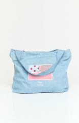 Model wearing a denim tote bag with a red and blue USA flag applique