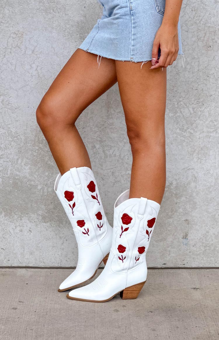 girl wearing white PU cowboy boots with red rose details and a denim mini skirt