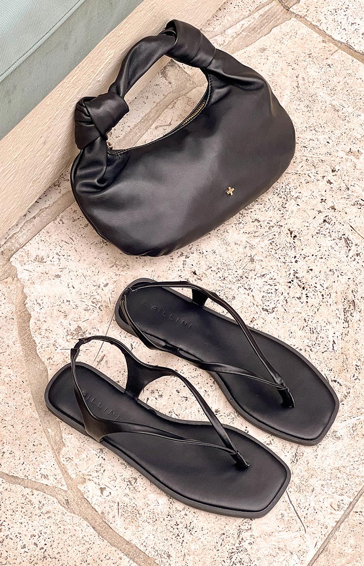 pinterest style flat lay of black billini sandals and a black peta and jain shoulder bag