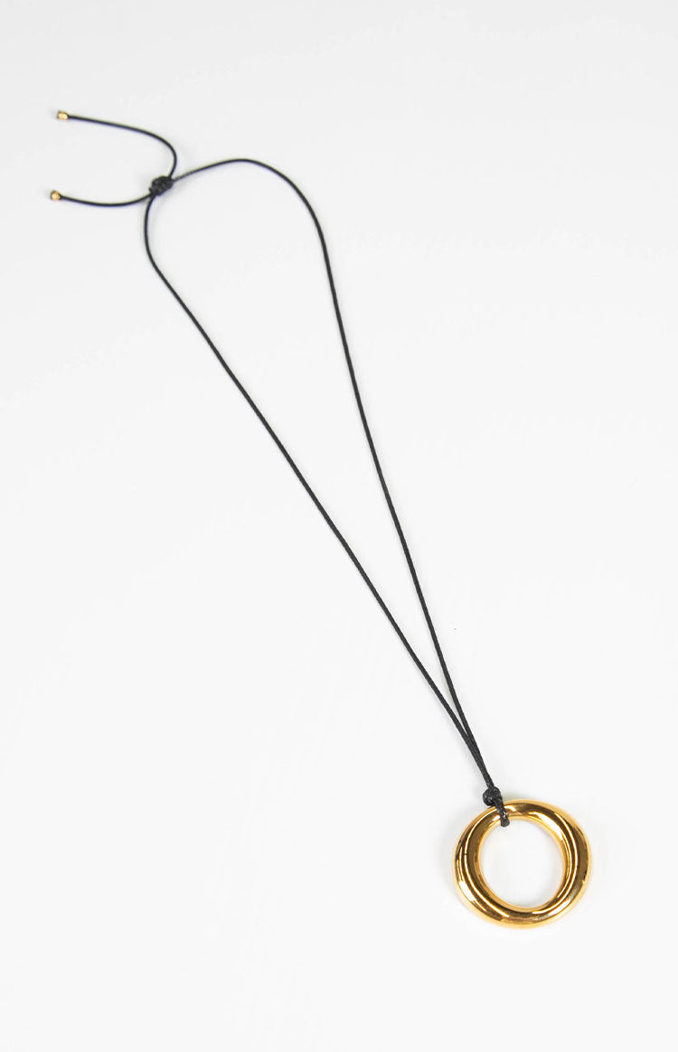 A simple gold pendant necklace with a circular charm on an adjustable black cord a chic accessory for any outfit