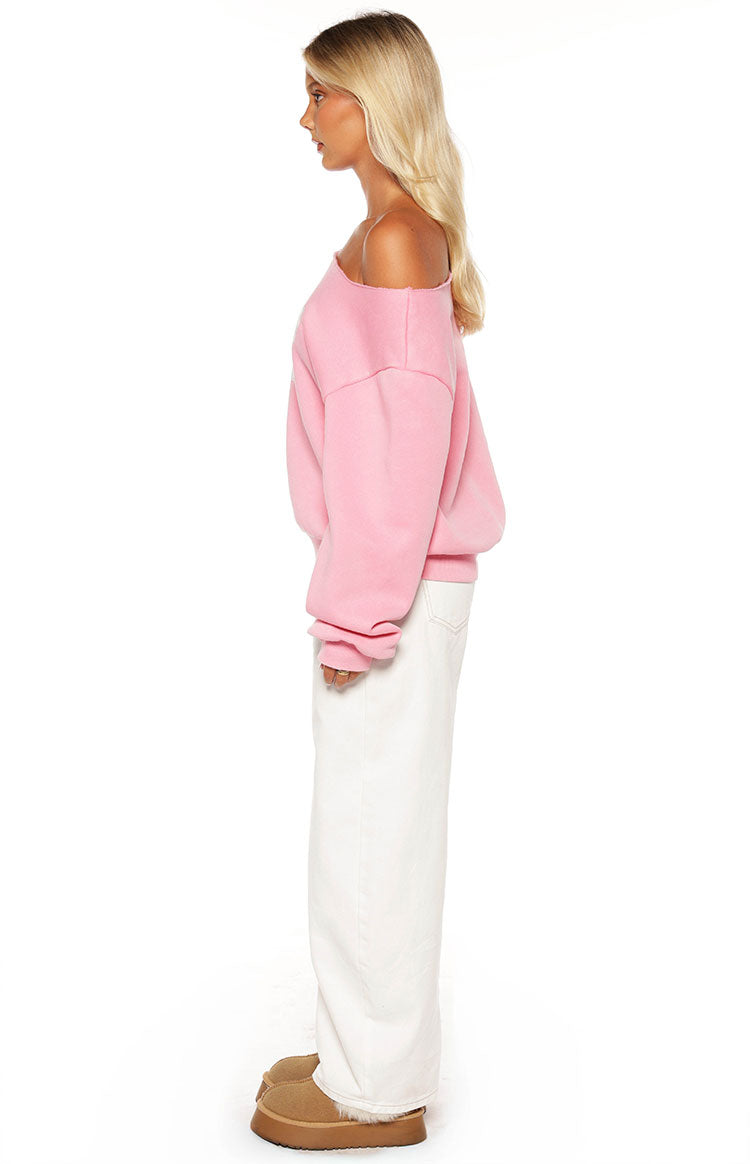 Woman sporting a trendy pink 97 off-shoulder sweatshirt and white wide-leg jeans for a comfy Spring style