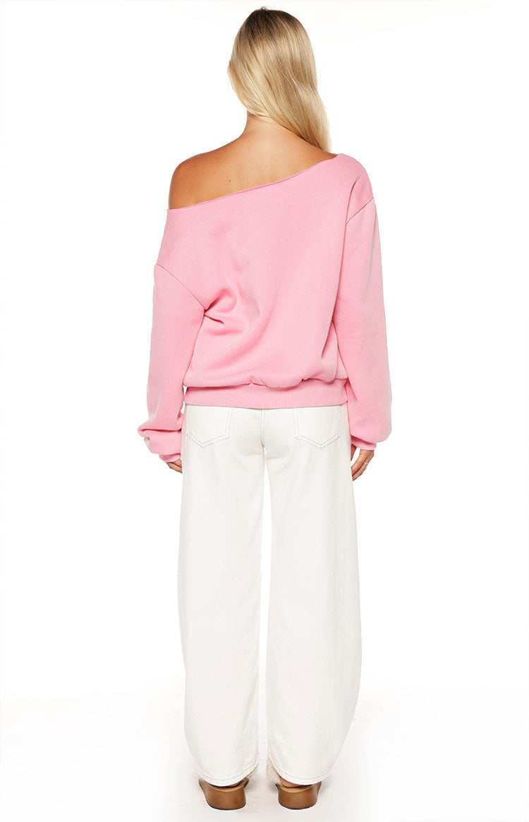 Woman sporting a trendy pink 97 off-shoulder sweatshirt and white wide-leg jeans for a comfy Spring style