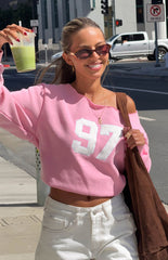 Girl in a vibrant pink 97 graphic off-shoulder top with white baggy jeans a casual look for Autumn street style