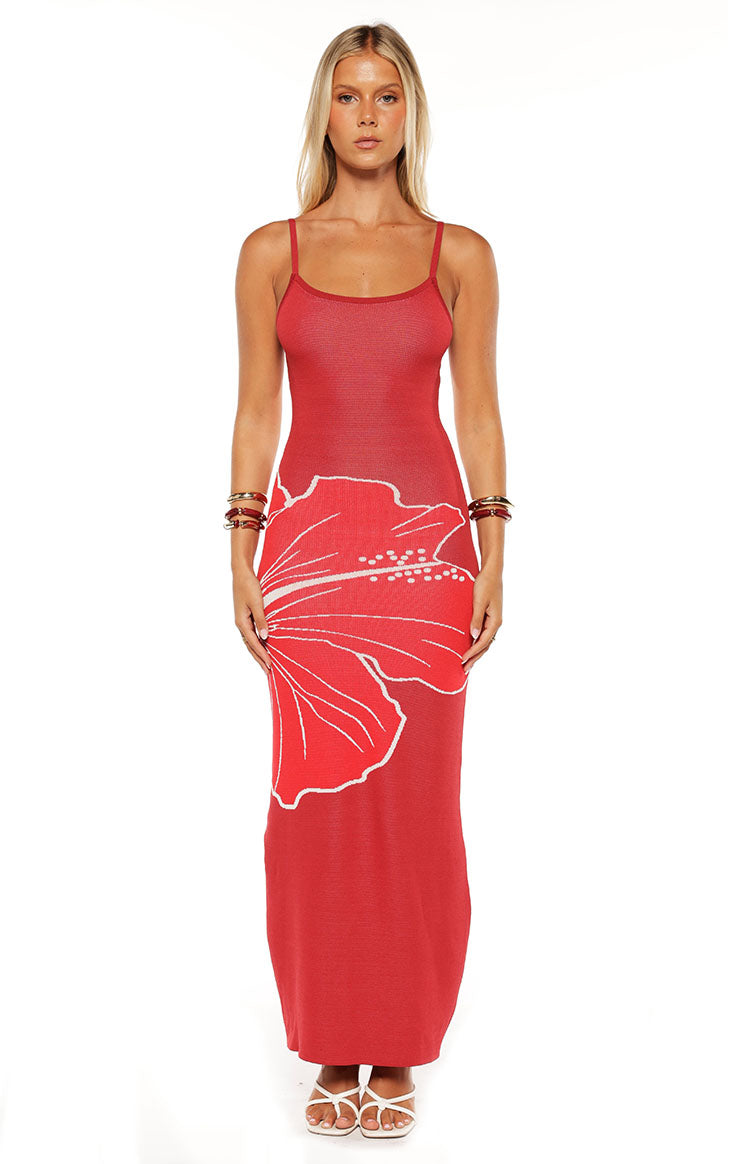 Model wears the Carly Red Knit Maxi Dress featuring a bold hibiscus print. This bodycon dress is a stunning choice for a summer vacation or beach party.