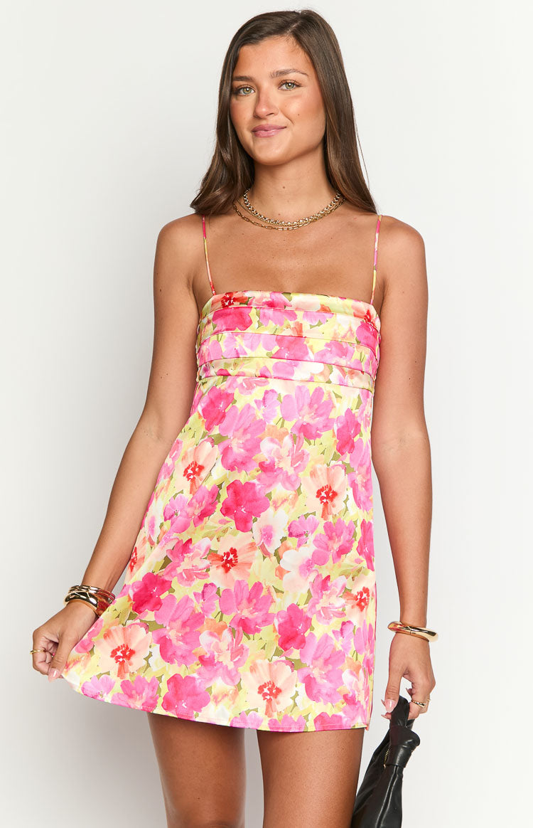 Fashion model showcasing a beautiful pink and yellow floral print mini slip dress- featuring delicate spaghetti straps and a flowing A-line silhouette- ideal for warm weather.