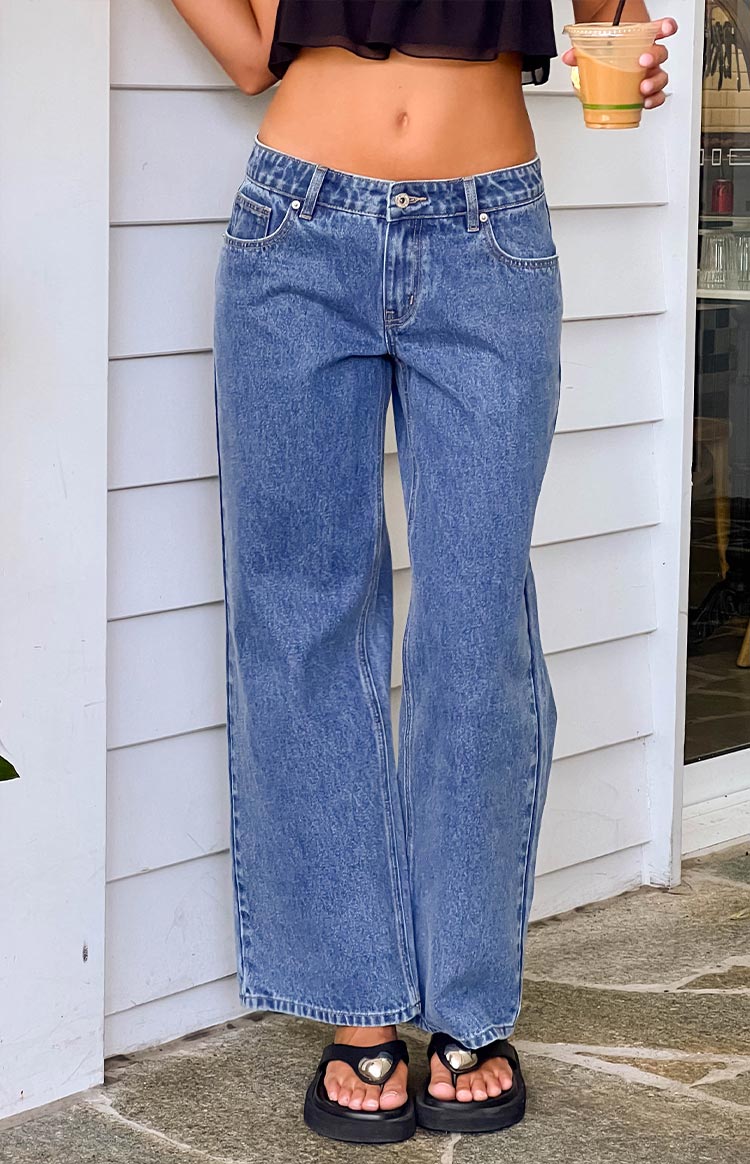 girl wearing low rise mid wash denim jeans paired with black sandals