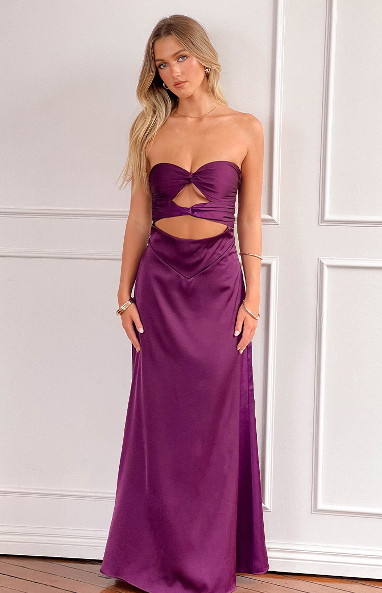 blonde model wearing a deep purple satin gown with cutout details at the bust, styled with a delicate gold necklace and gold bracelets