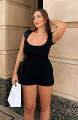Black short playsuit with scoop neckline and short sleeves worn by brunette model.