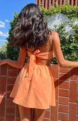 brunette model wearing orange strapless tie up mini dress