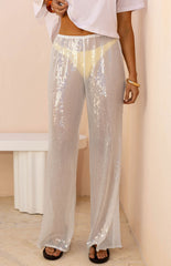 Our model wearing sheer white sequin pants with a wide-leg cut perfectly wear over a pair of bikini bottoms.