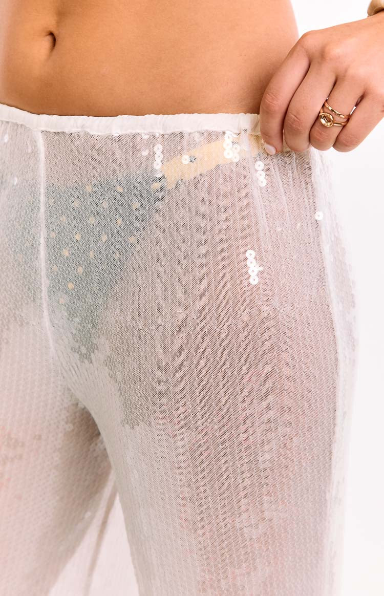 A close-up of our model's waist and hips showing a pair of sheer white sequin pants with a wide-leg cut. You can see through the pants to any bikini bottom.