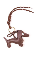A gold dachshund shaped bag charm with a braided tan strap. This cute accessory features a clasp to attach to a handbag or keys. A perfect novelty gift for a dog lover or a fun addition to a casual outfit.