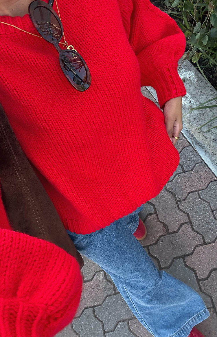 girl is wearing flare mid-wash and rise fitted jeans paired with a red oversized knit sweater