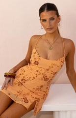 Our model wearing a peach-colored mini dress with a floral pattern and all-over gold sequins and bead embellishments. This dress has a deep neckline in thin straps and a short slit on the side.