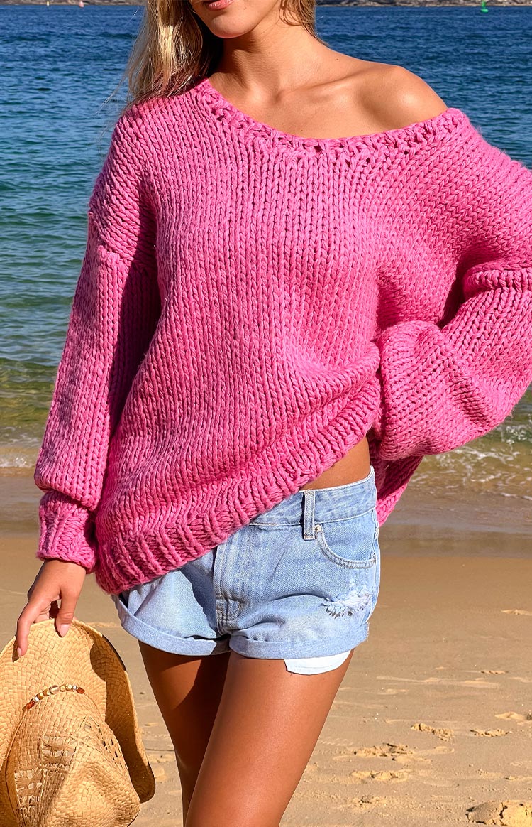 Model wearing a hot pink chunky knit sweater and blue denim shorts.