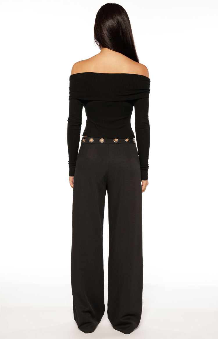 Model wearing a chic black off-shoulder long-sleeve top and wide-leg trousers perfect for a sophisticated evening out