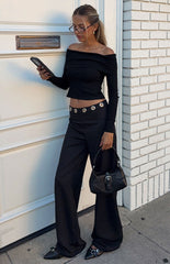 Model wearing a chic black off-shoulder long-sleeve top and wide-leg trousers perfect for a sophisticated evening out