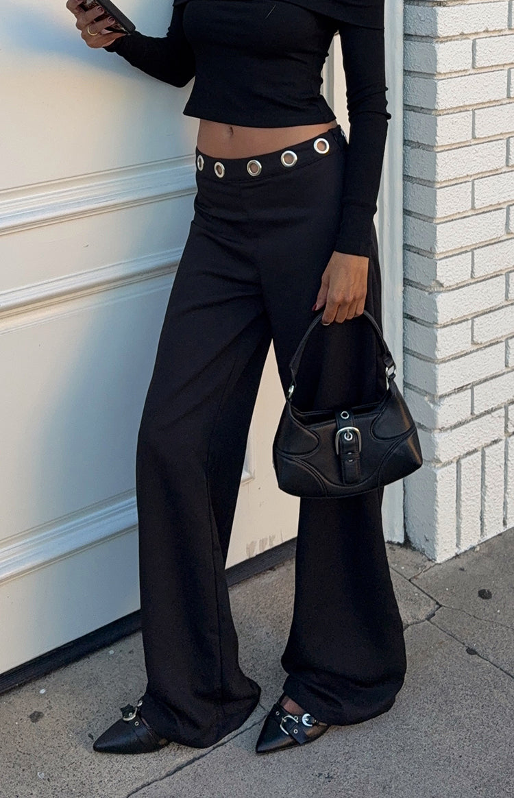 Model wearing a chic black off-shoulder long-sleeve top and wide-leg trousers perfect for a sophisticated evening out