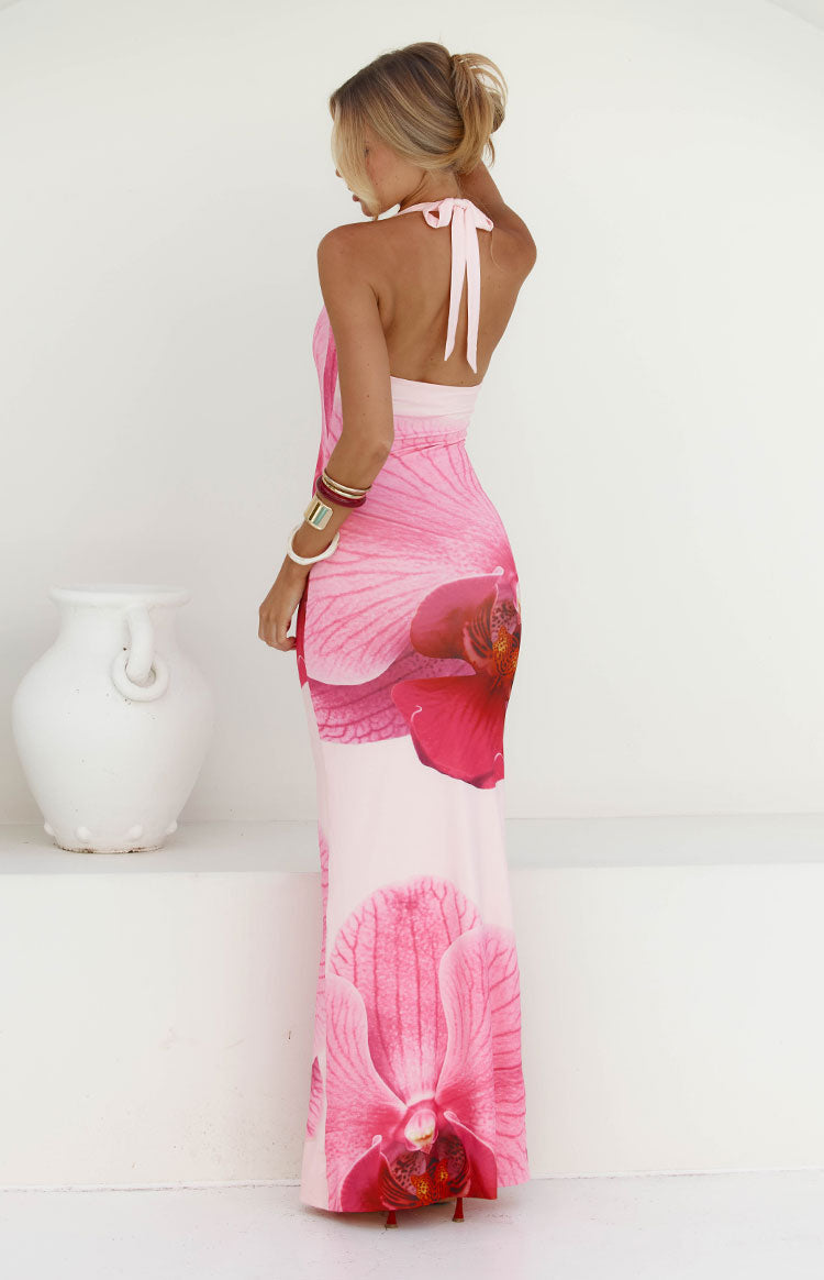 Our model wearing a light pink halter-style maxi dress with a large vibrant pink floral print. The dress has a plunging V-neckline and a subtle ruching detail.
