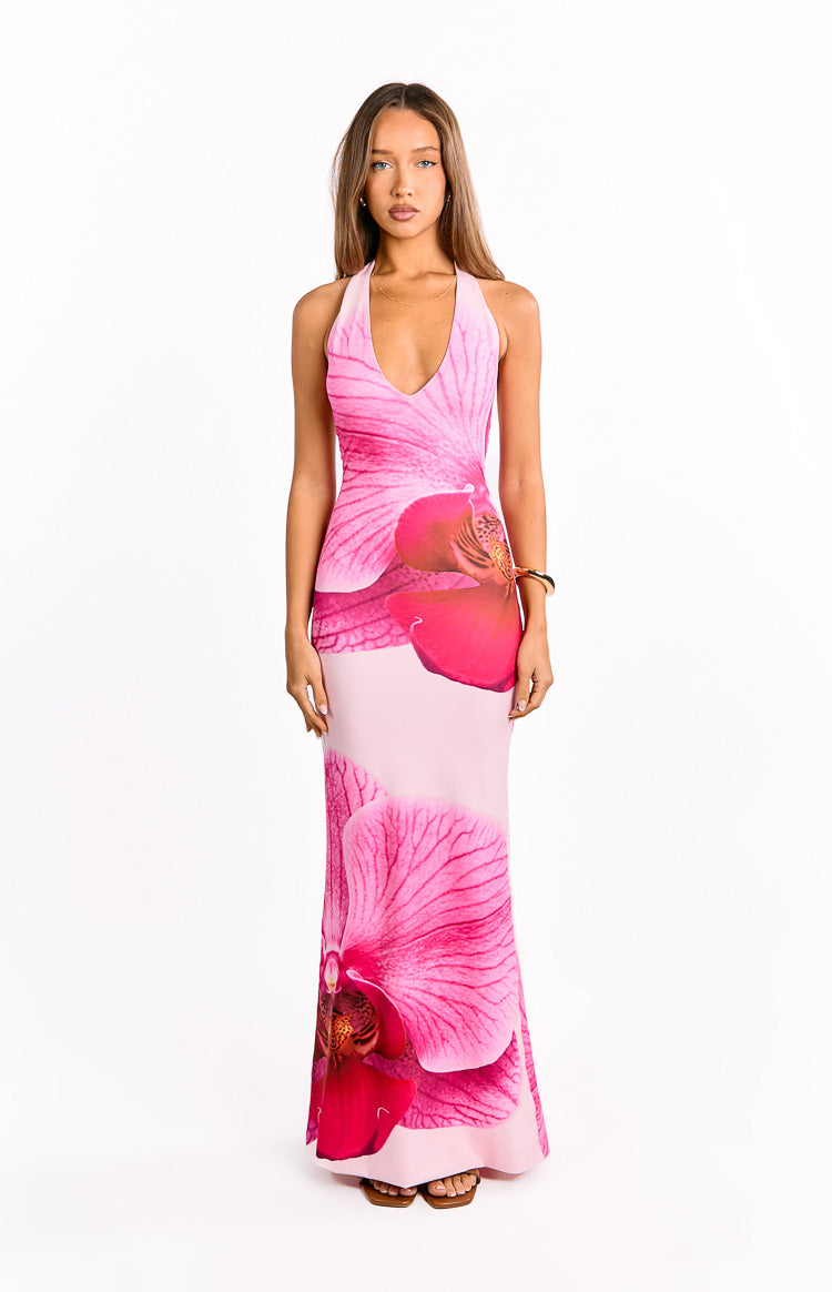 Our model wearing a light pink halter-style maxi dress with a large vibrant pink floral print. The dress has a plunging V-neckline and a subtle ruching detail.