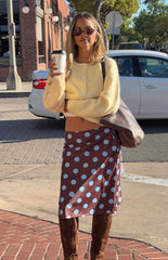 Fashionable woman wearing a cozy yellow button-up cardigan and a brown polka dot midi skirt a perfect Autumn style