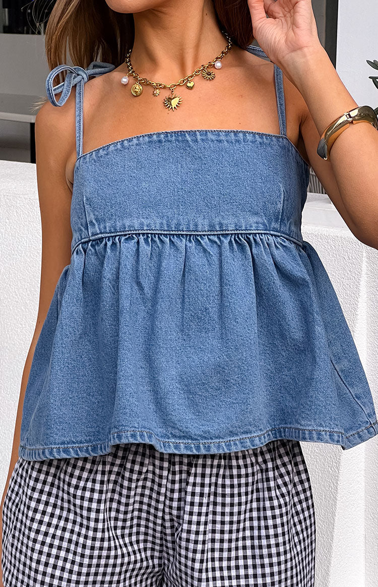 Model wears a sleeveless blue denim top for a casual street style look.