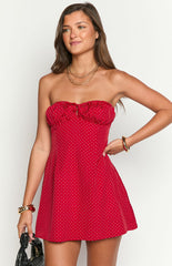 Fashion model showcasing a playful red and white polka dot strapless mini dress with a ruffled neckline and charming front tie- perfect for a casual or festive occasion.