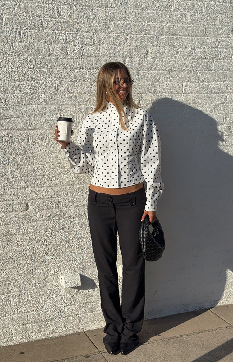 Girl wearing a chic white polka dot long-sleeve shirt and black tailored pants an elegant outfit for a Fall gathering