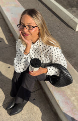Woman in a trendy white polka dot high-neck jacket and black trousers a professional yet stylish look for work or events