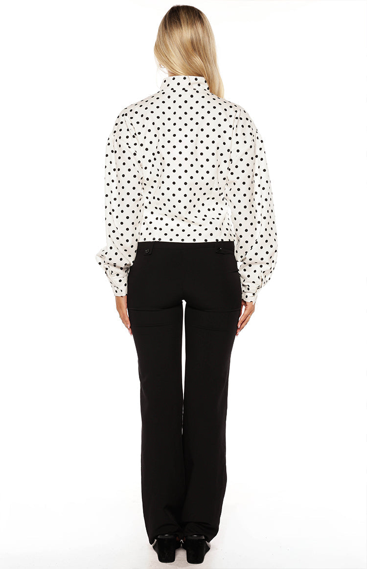 Woman in a trendy white polka dot high-neck jacket and black trousers a professional yet stylish look for work or events