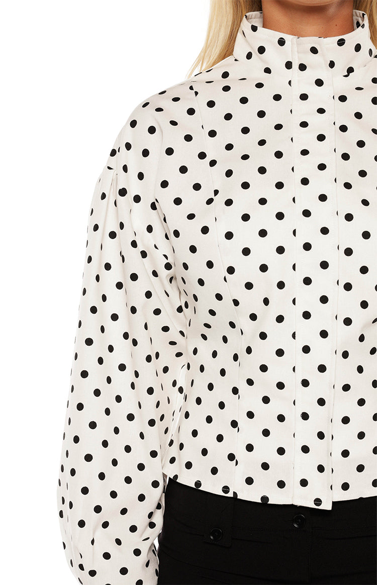 Woman in a trendy white polka dot high-neck jacket and black trousers a professional yet stylish look for work or events