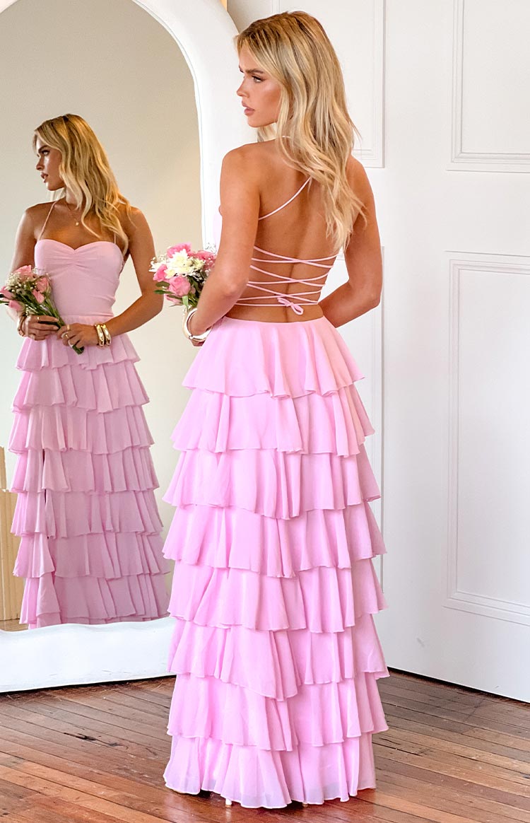 girl wearing a pink maxi dress with a tiered ruffle skirt and open back with adjustable tie details