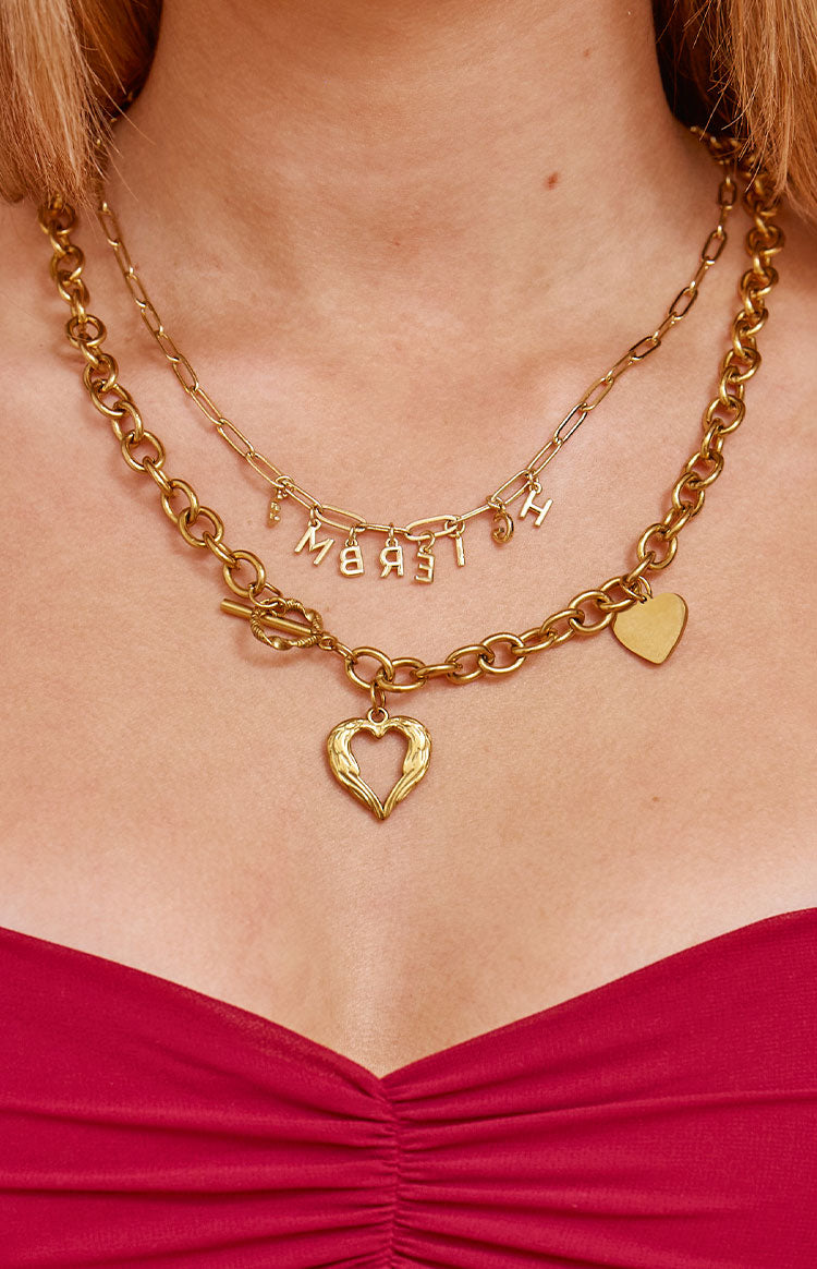 A chunky gold-toned necklace featuring a toggle clasp and an open heart pendant accompanied by a smaller solid heart charm.