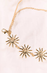 A gold-toned chain belt featuring a lobster clasp closure and three prominent sun charms with faces. The charms are linked together by a thinner chain.