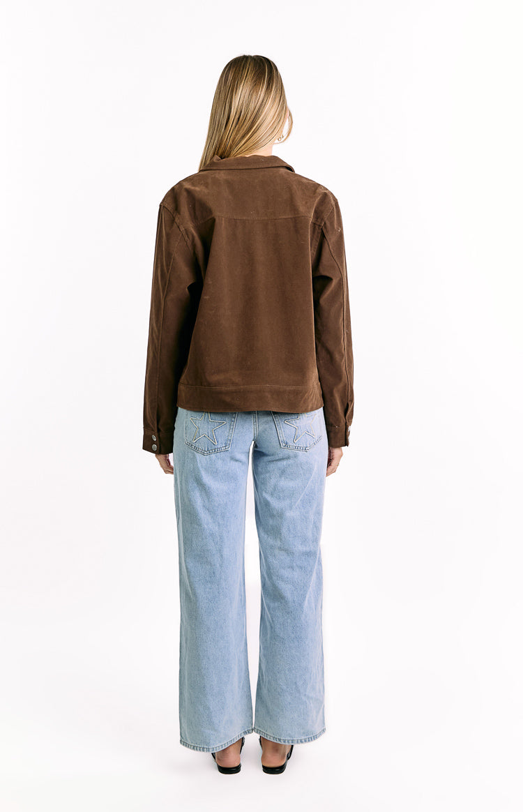 and silver snap buttons down the front. The jacket is worn open over a black crop top.