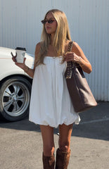 Model in a playful white strapless bubble mini dress with brown knee-high boots a fun look for a Spring festival
