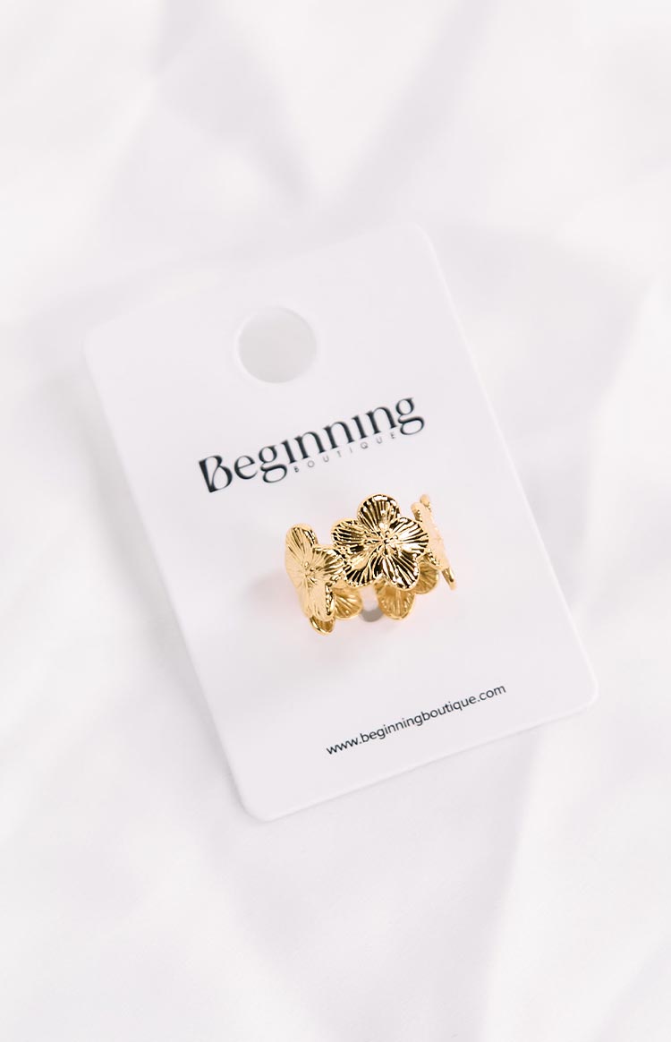A gold flower-shaped ring displayed on a white 'Beginning Boutique' branded card.