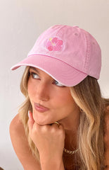 Blonde model wearing a washed pink baseball cap with an embroidered floral graphic