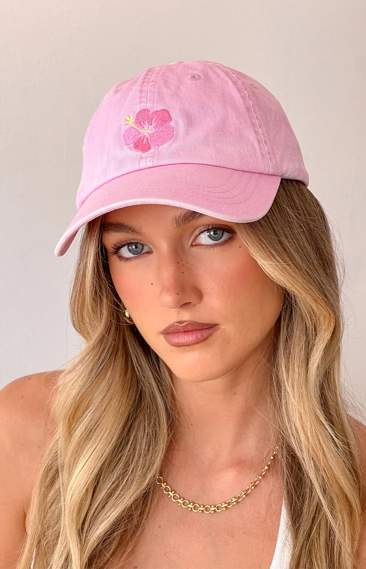 Girl wearing a light pink dad cap hat with a hibiscus graphic detail