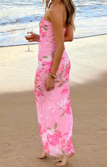 The side view of a strapless pink maxi-dress with a ruched bodice and a flowing skirt- adorned with a large pink and green floral print.