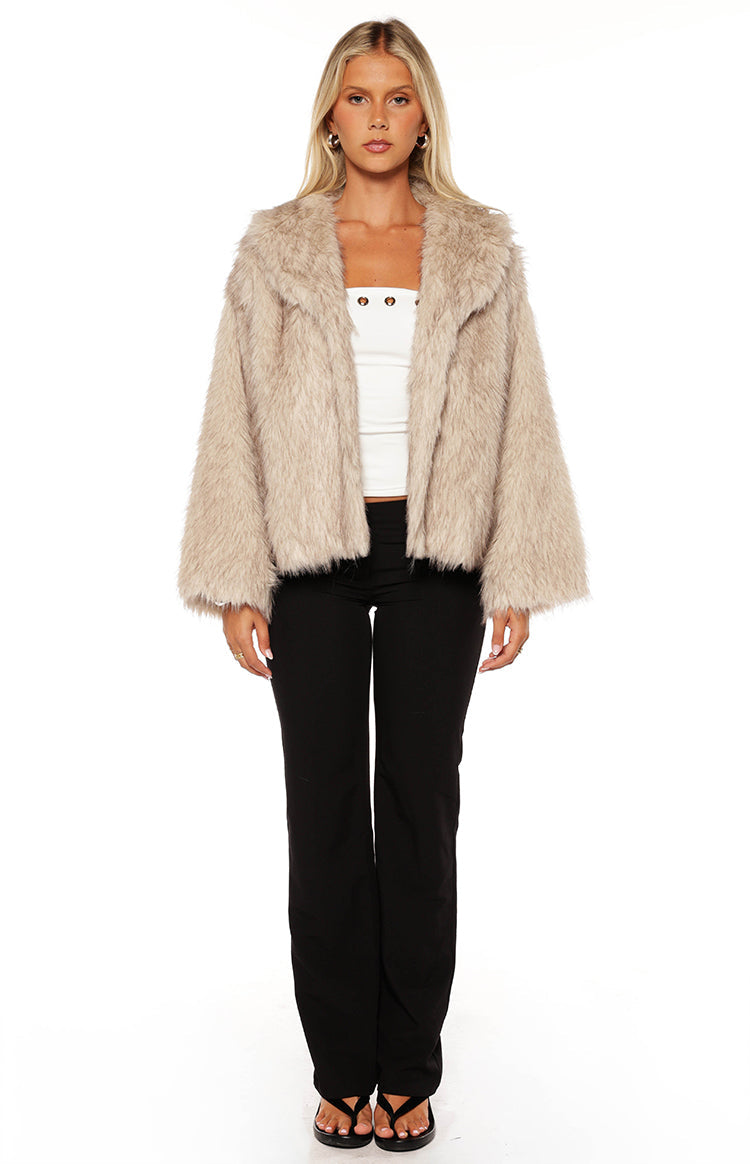 Woman wearing a luxurious sand faux fur jacket with wide leg jeans a glamorous choice for an Autumn event