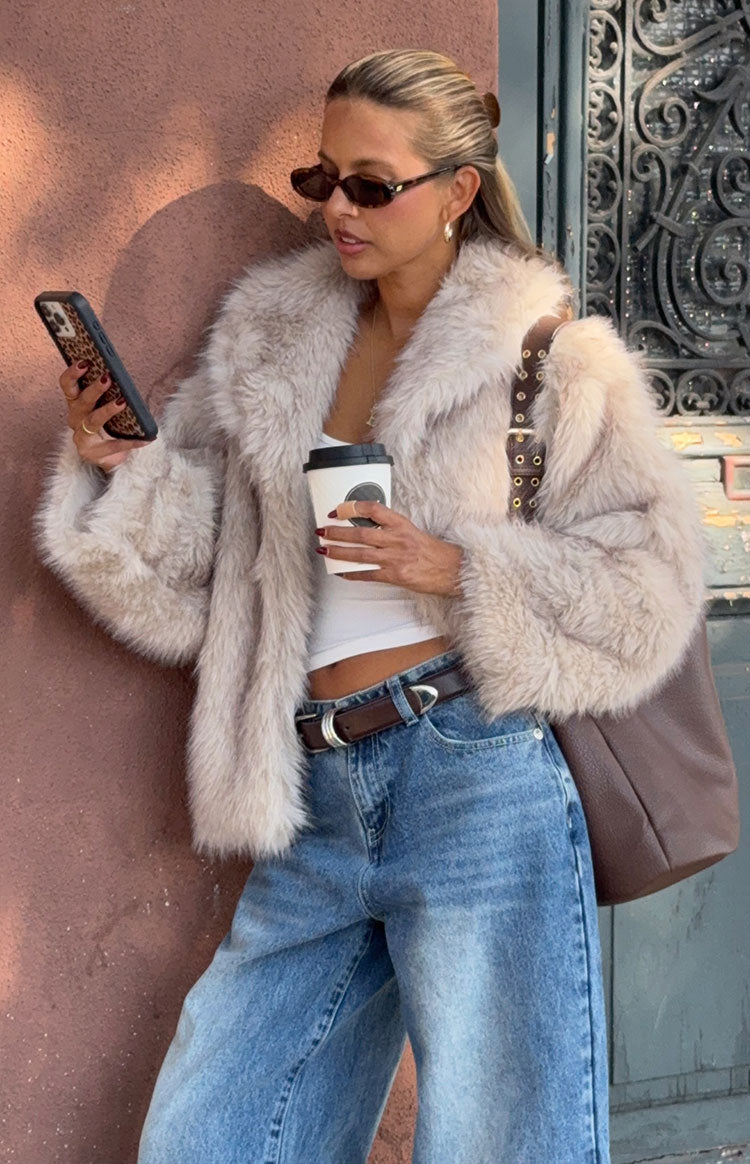 Woman wearing a luxurious sand faux fur jacket with wide leg jeans a glamorous choice for an Autumn event