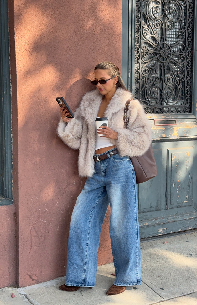 Woman wearing a luxurious sand faux fur jacket with wide leg jeans a glamorous choice for an Autumn event