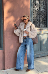 Woman wearing a luxurious sand faux fur jacket with wide leg jeans a glamorous choice for an Autumn event