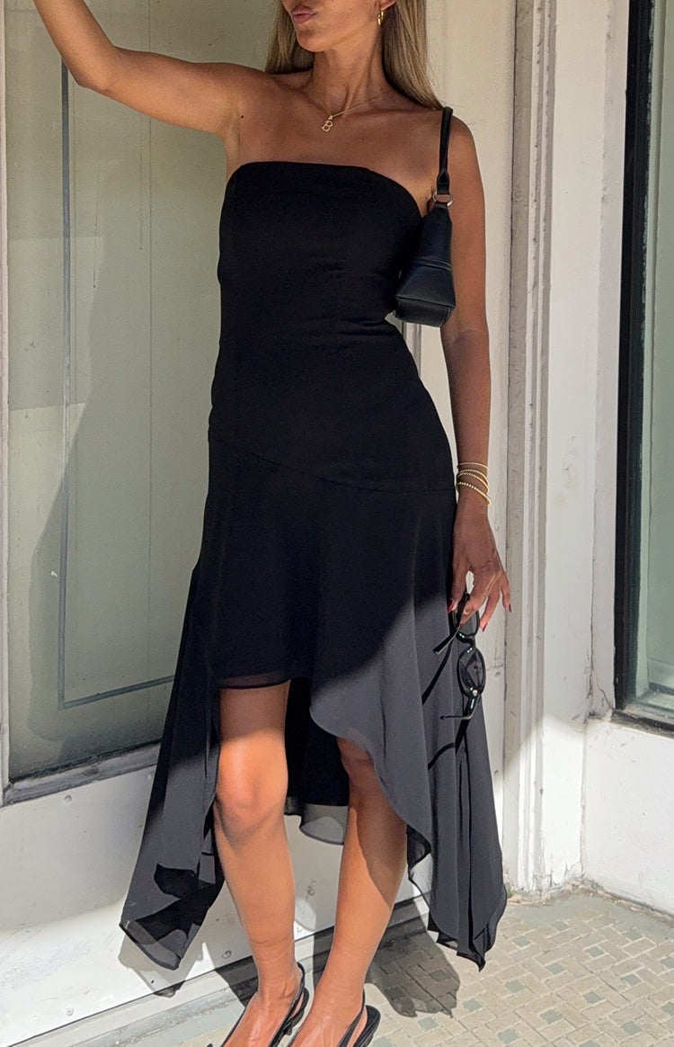 Model taking a selfie in a black strapless midi dress with a stylish asymmetrical hanky hem
