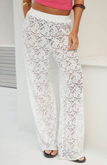 A full-length image of our model wearing a pair of sheer white lace pants with a floral pattern and a wide-leg cut.