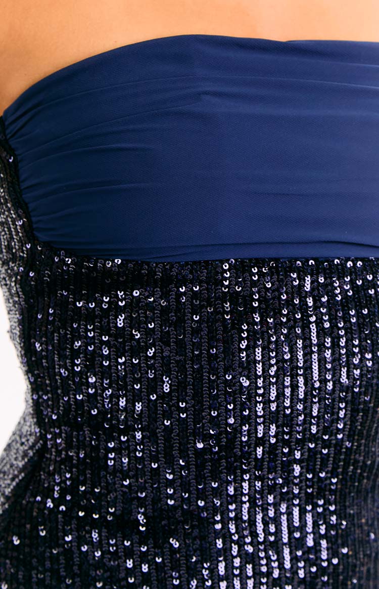 Model wears a navy blue sequin mini dress. This sparkling party dress features a strapless neckline and a flattering bodycon silhouette. The perfect choice for a birthday or New Years Eve event.