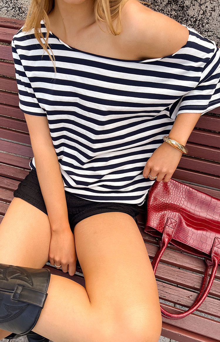 Our model wearing an oversized navy blue and white striped t-shirt with a wide slouchy neckline that falls off one shoulder. Perfect for your next festival events!