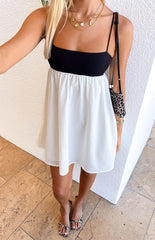 Girl wearing a white and black contrast babydoll mini dress paired with leopard print shoes and bag