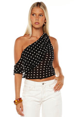 Close up of a chic black and white polka dot top with a one shoulder design a playful choice for a night out or party